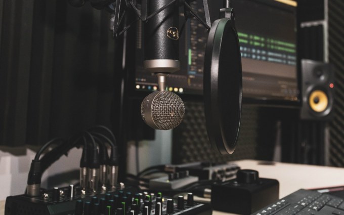 At home podcast recording set up with a microphone, pop filter, and computer